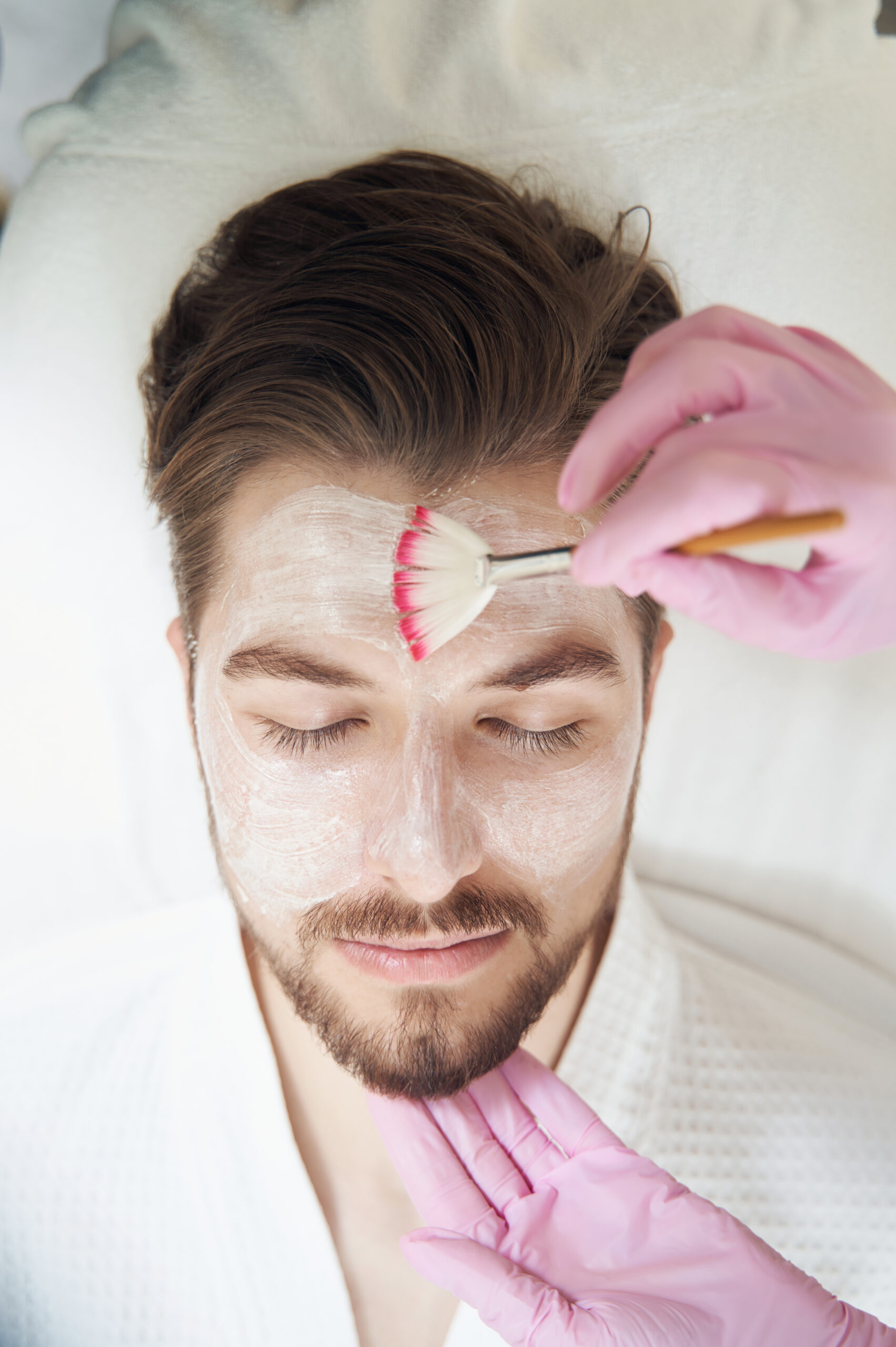 Man receiving a luxurious facial treatment with a facial brush applied to forehead